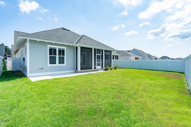 rear view of property with a sunroom, a fenced backyard, a lawn, and roof with shingles