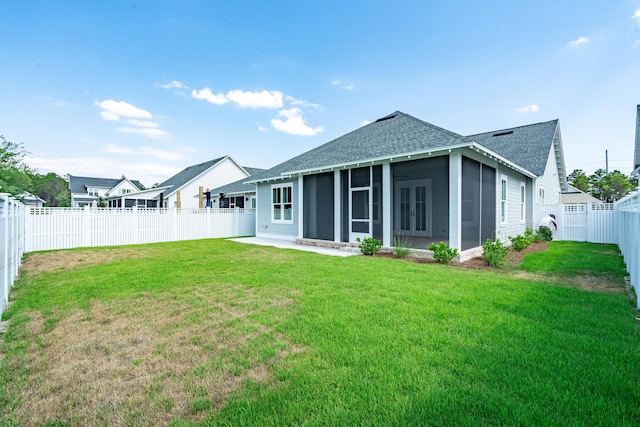 rear view of house with a yard, a shingled roof, a fenced backyard, and a sunroom