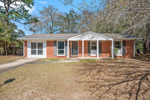 ranch-style home featuring brick siding, a shingled roof, fence, a front yard, and driveway