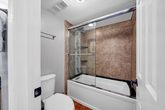 bathroom featuring hardwood / wood-style flooring, toilet, and enclosed tub / shower combo