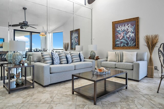 tiled living room with ceiling fan and a towering ceiling