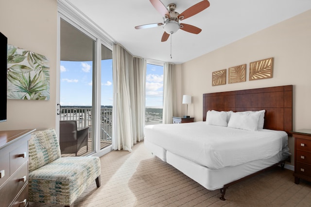 bedroom featuring expansive windows, ceiling fan, and access to outside