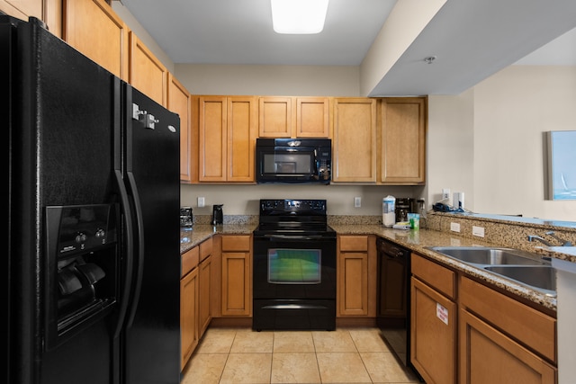 kitchen with kitchen peninsula, black appliances, light stone counters, sink, and light tile floors