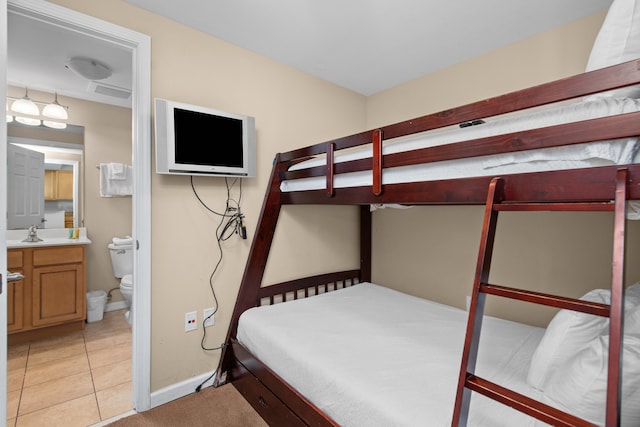 bedroom featuring sink, light tile floors, and ensuite bathroom