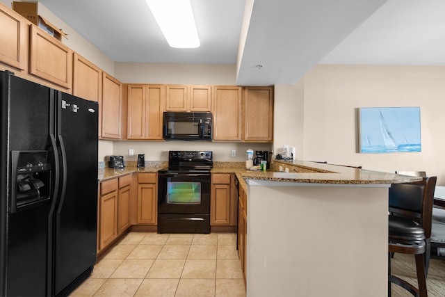 kitchen featuring light tile flooring, light stone countertops, black appliances, kitchen peninsula, and a kitchen bar