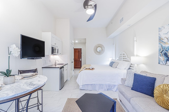 tiled bedroom featuring sink, ceiling fan, and ensuite bath