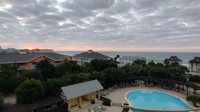 pool at dusk with a patio and a water view