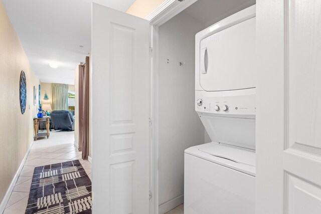 clothes washing area featuring light tile patterned flooring and stacked washer / dryer