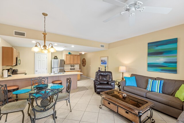 tiled living room featuring ceiling fan with notable chandelier