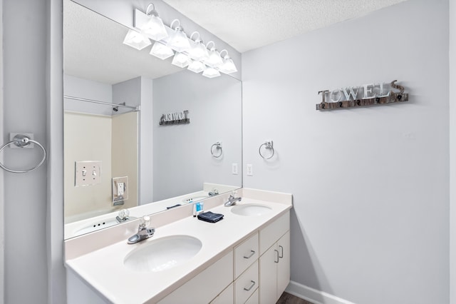 bathroom featuring a textured ceiling, large vanity, and dual sinks