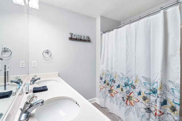 bathroom featuring a textured ceiling and double sink vanity