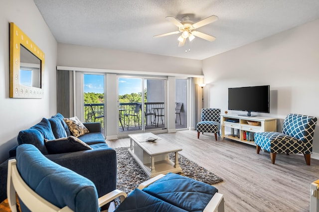 living room with light hardwood / wood-style flooring, ceiling fan, and a textured ceiling