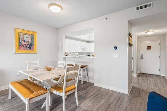 dining space with a textured ceiling and hardwood / wood-style floors