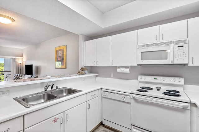 kitchen with sink, white appliances, kitchen peninsula, and white cabinetry