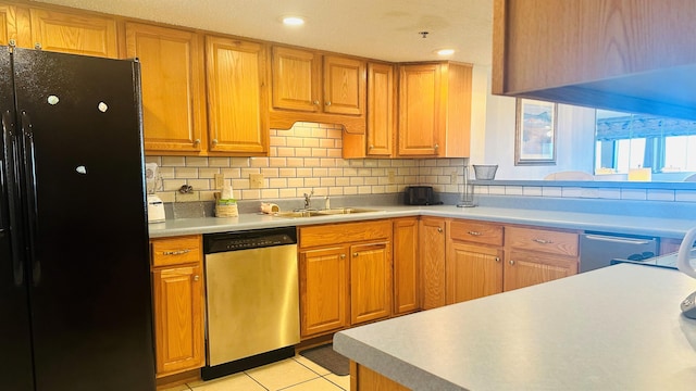 kitchen with black fridge, backsplash, sink, light tile floors, and stainless steel dishwasher