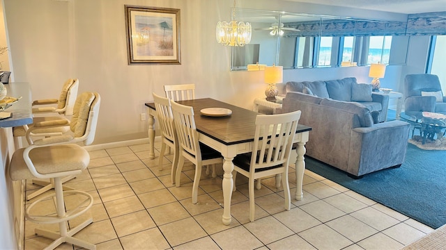 tiled dining room featuring ceiling fan with notable chandelier