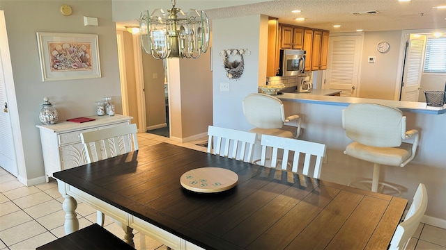 dining area featuring a textured ceiling, light tile floors, and a chandelier