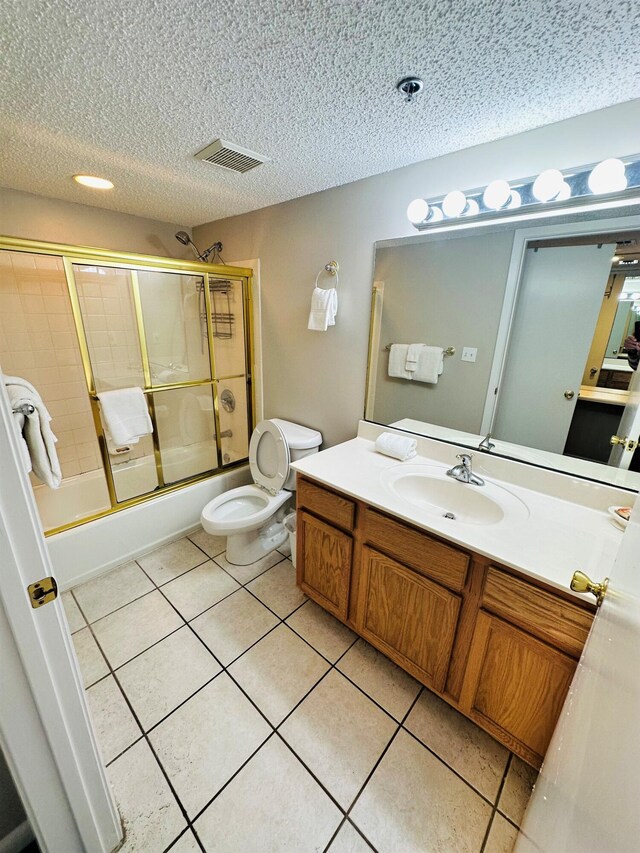 bathroom with toilet, tile floors, vanity, and a textured ceiling