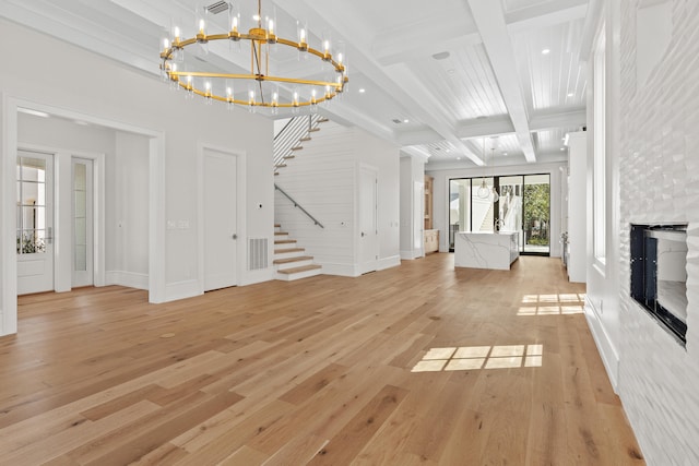 unfurnished living room with a chandelier, beam ceiling, and light wood-type flooring