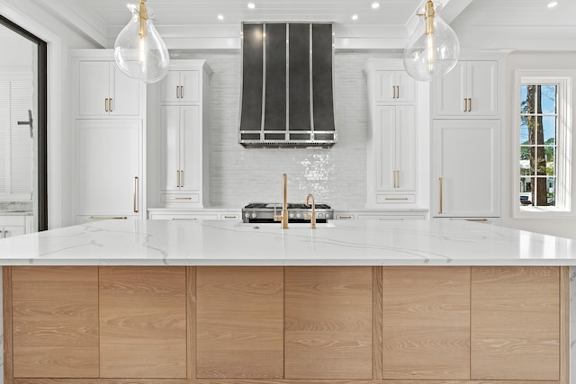 kitchen featuring white cabinets, an island with sink, and light stone countertops