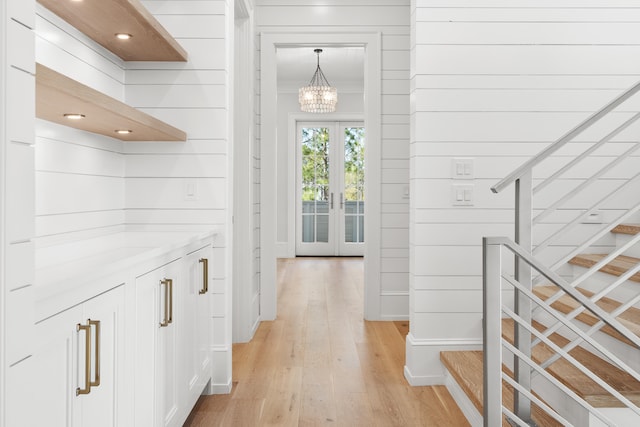 hall with a notable chandelier, light hardwood / wood-style flooring, and french doors