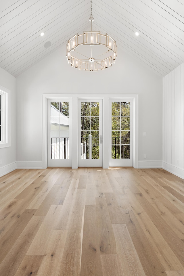 empty room with lofted ceiling, light hardwood / wood-style floors, and an inviting chandelier