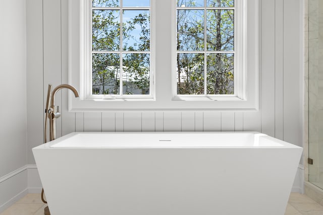 bathroom with a bath, a healthy amount of sunlight, and tile floors