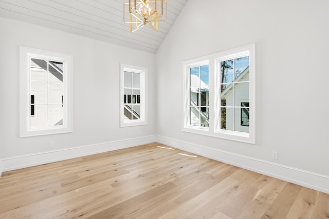 spare room featuring vaulted ceiling, light hardwood / wood-style floors, and an inviting chandelier