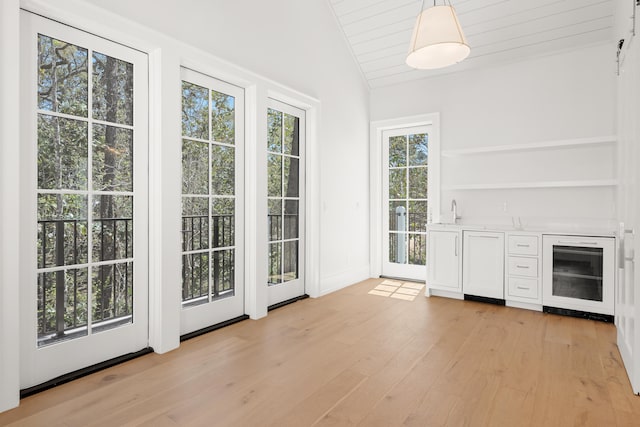 doorway featuring sink, vaulted ceiling, and light wood-type flooring