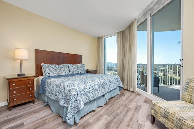 bedroom featuring light hardwood / wood-style flooring, expansive windows, and access to exterior