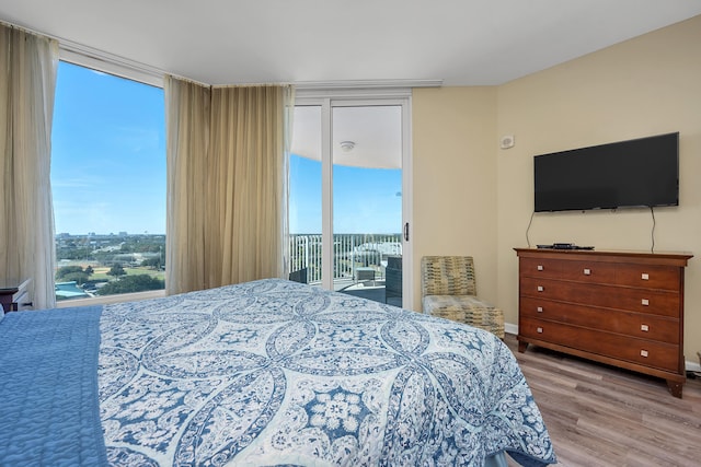 bedroom with expansive windows, light wood-type flooring, and access to exterior