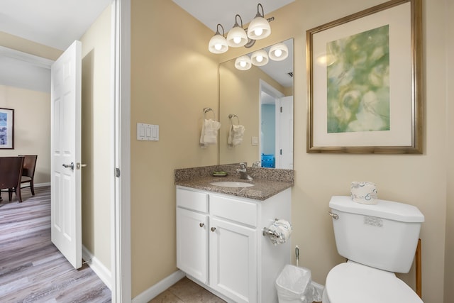 bathroom with vanity with extensive cabinet space, wood-type flooring, toilet, and a chandelier