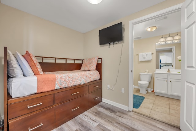 bedroom with light hardwood / wood-style flooring and ensuite bath