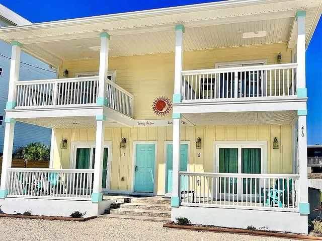 rear view of house featuring a balcony and a porch