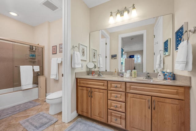 full bathroom with tile flooring, large vanity, double sink, toilet, and bath / shower combo with glass door