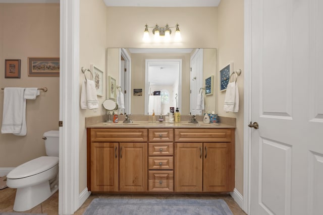 bathroom featuring vanity with extensive cabinet space, double sink, toilet, and tile floors