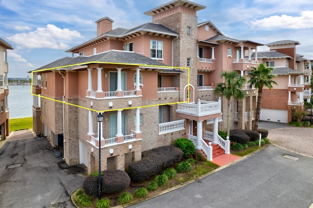 view of front facade with a water view, a garage, and a balcony