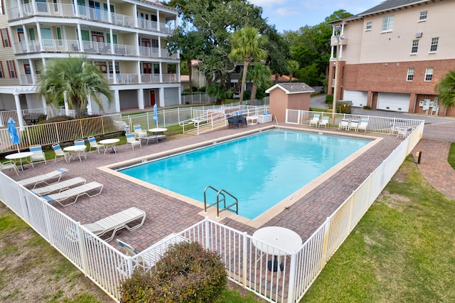 view of swimming pool featuring a patio, a yard, and an outdoor structure