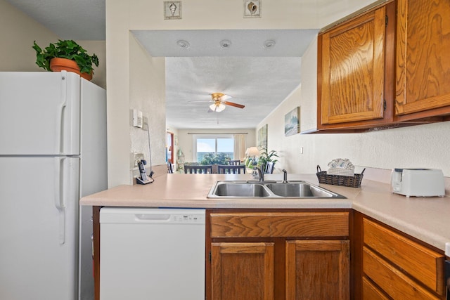 kitchen featuring sink, white appliances, ceiling fan, and a textured ceiling