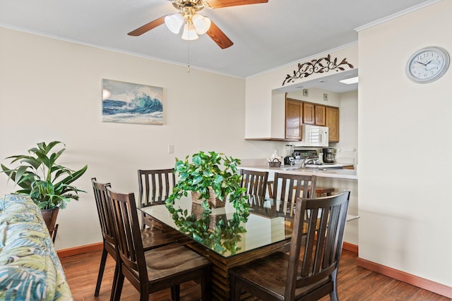 dining room featuring ceiling fan, crown molding, and dark wood-type flooring