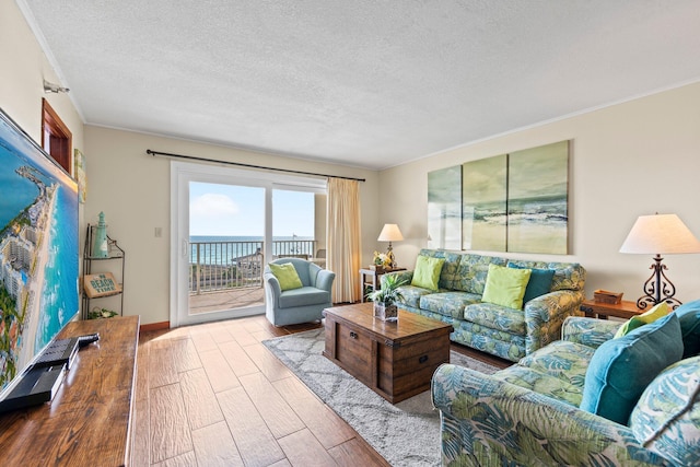 living room with a water view, a textured ceiling, light hardwood / wood-style floors, and crown molding