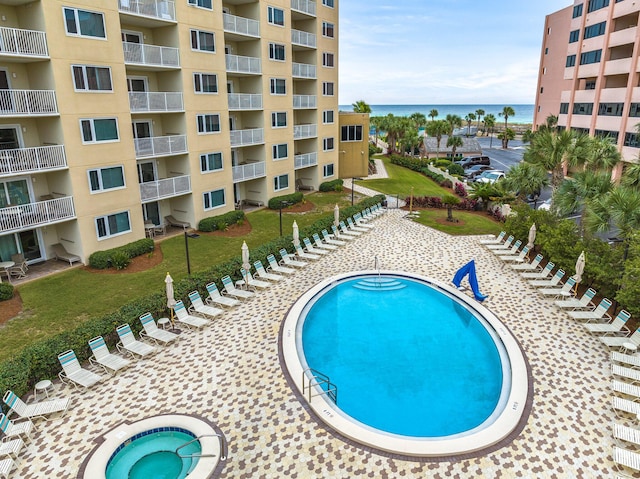 view of swimming pool with a water view, a yard, and a community hot tub