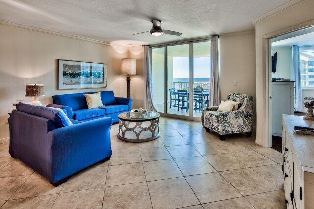 living room with a textured ceiling, a wealth of natural light, ceiling fan, and light tile floors