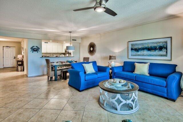 tiled living room with ornamental molding, ceiling fan, and a textured ceiling