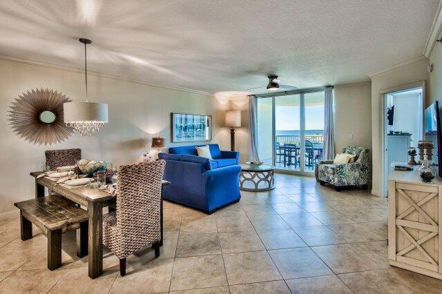 tiled living room with ornamental molding, ceiling fan, a textured ceiling, and expansive windows