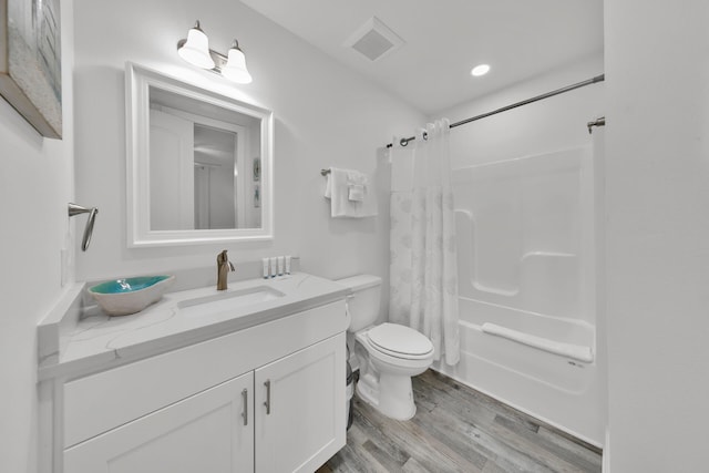 full bathroom featuring hardwood / wood-style flooring, toilet, shower / bath combo, and vanity