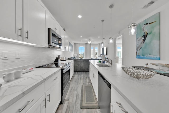 kitchen featuring tasteful backsplash, stainless steel appliances, light wood-type flooring, and white cabinetry