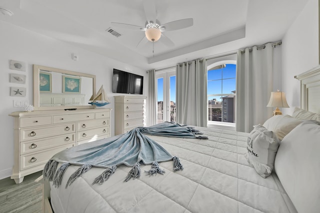 bedroom featuring a raised ceiling, ceiling fan, and hardwood / wood-style flooring