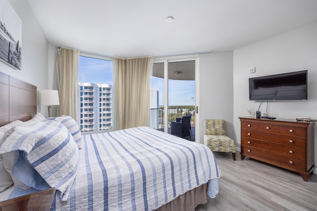 bedroom featuring light wood-type flooring, access to outside, and expansive windows