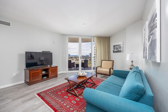 living room featuring a wall of windows and light wood-type flooring